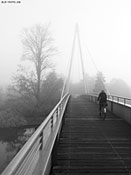 Radfahrerin auf Brücke im Nebel