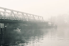 Angler unter Brücke im Nebel